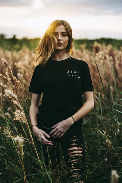 白天站在棕色麦田上的黑色圆领t恤和黑色旧底的选择性聚焦摄影